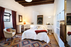Une chambre à coucher avec un lit, une chaise, un bureau et une lampe.