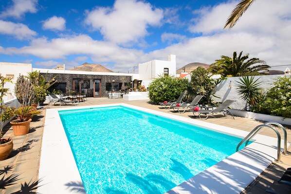 A swimming pool with lounge chairs and potted plants. - Rustic Home Short Drive from Beach with Pool, Terraces & Garden (Güime)