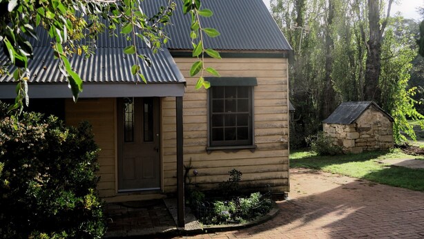 Una casa de madera con techo de metal, una puerta principal y un pequeño jardín.