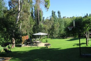 Un patio trasero con zona de barbacoa, una mesa de comedor y un aro de baloncesto.