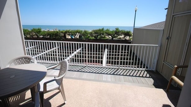 Un balcon avec vue sur la mer, une table et des chaises.