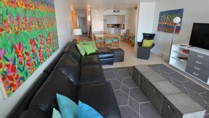 Un salon comprenant un canapé, un pouf et un grand tableau abstrait accroché au mur.