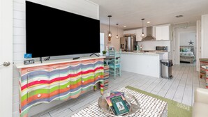 Ett modernt kök med en stor TV, ett randigt skåp och en liten köksö med böcker.