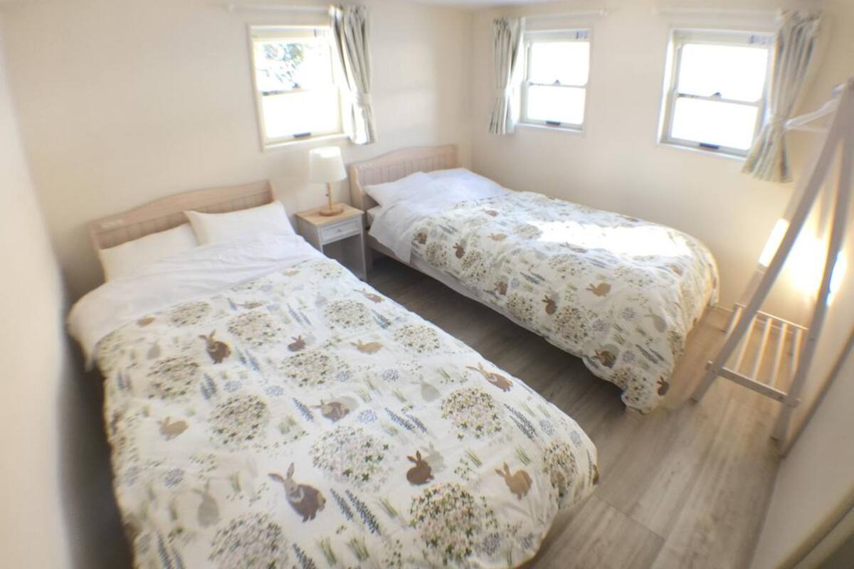 Un dormitorio con dos camas, una mesita de noche y un ventanal.