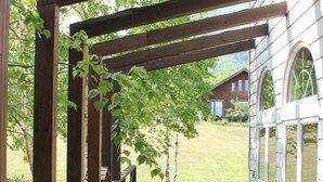 A wooden deck with a pergola structure, leading to a building with large windows. - Rusutsu Pension Clydesdale (Rusutsu)