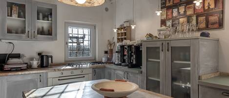 Una cocina con una isla grande, electrodomésticos de acero inoxidable y decoración de pared de estilo vintage.
