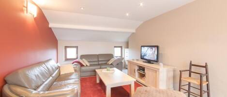 A modern living room with a sofa, a coffee table, and a television.