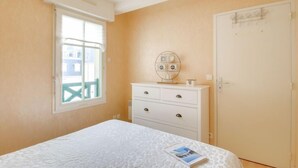 Un dormitorio con cama, cómoda, ventana y puerta.