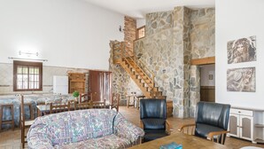 A spacious living area with a patterned sofa, leather chairs, a wooden coffee table, and a stone wall. - Rustic Villa Close to Beach with Pool, Terrace & Wi-Fi; Pets Allowed, Parking Available (Conil de la Frontera)