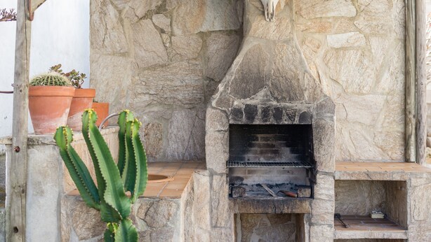 A stone-built outdoor oven with a rustic design, surrounded by potted plants and a cactus. - Rustic Villa Close to Beach with Pool, Terrace & Wi-Fi; Pets Allowed, Parking Available (Conil de la Frontera)