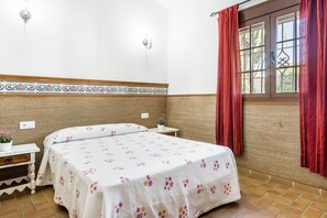 A room with a bed, a nightstand, a window with curtains, and a wall with a decorative border.