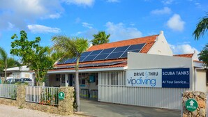 Un edificio con letreros que indican 'Drive Thru VIP Diving' y 'Scuba Tanks', y una entrada con muro de piedra.
