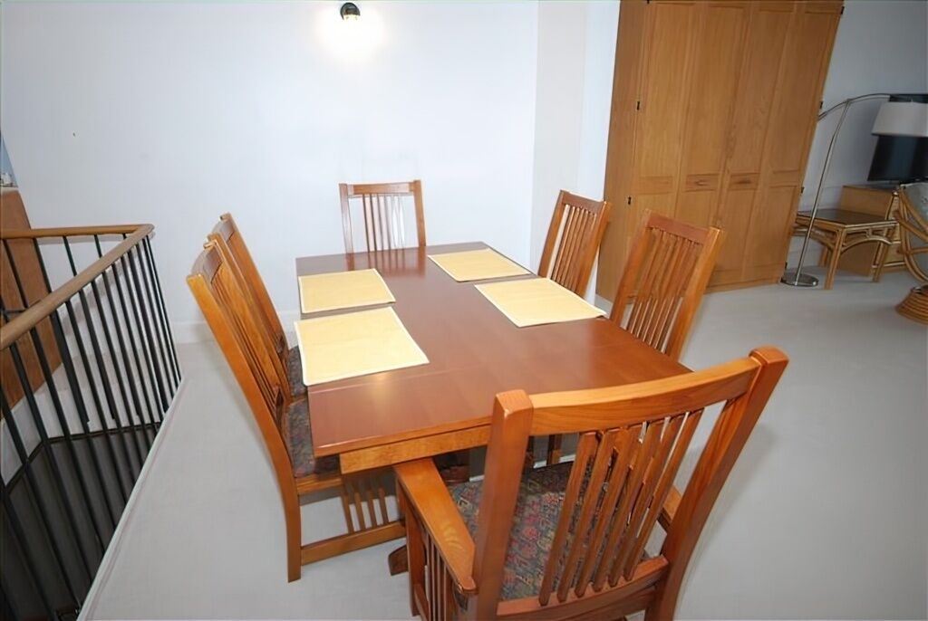 A conference room with a wooden table, six chairs, and a large wardrobe.