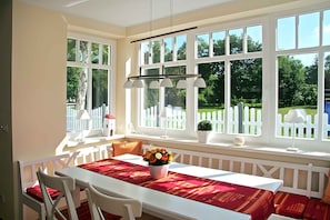 Enjoy a serene view of lush greenery from the comfort of this room, featuring a table and chairs by the window.