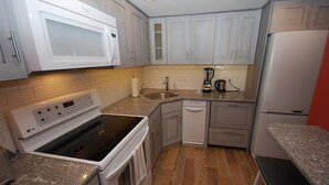 A modern kitchen with white cabinets, a built-in microwave, a stove, and a sink. - Edgewater House - Ocean Front Units With Spectacular Views! (Rehoboth Beach)