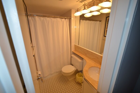 A bathroom with a toilet, sink, and shower curtain. - Edgewater House - Ocean Front Units With Spectacular Views! (Rehoboth Beach)