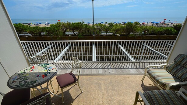 A balcony with a view of the beach, a table with chairs, and a sofa. - Edgewater House - Ocean Front Units With Spectacular Views! (Rehoboth Beach)