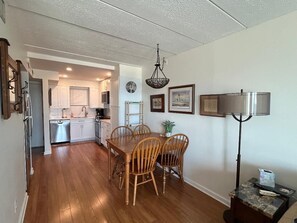 A dining area with a wooden table and chairs, a chandelier, and a floor lamp.