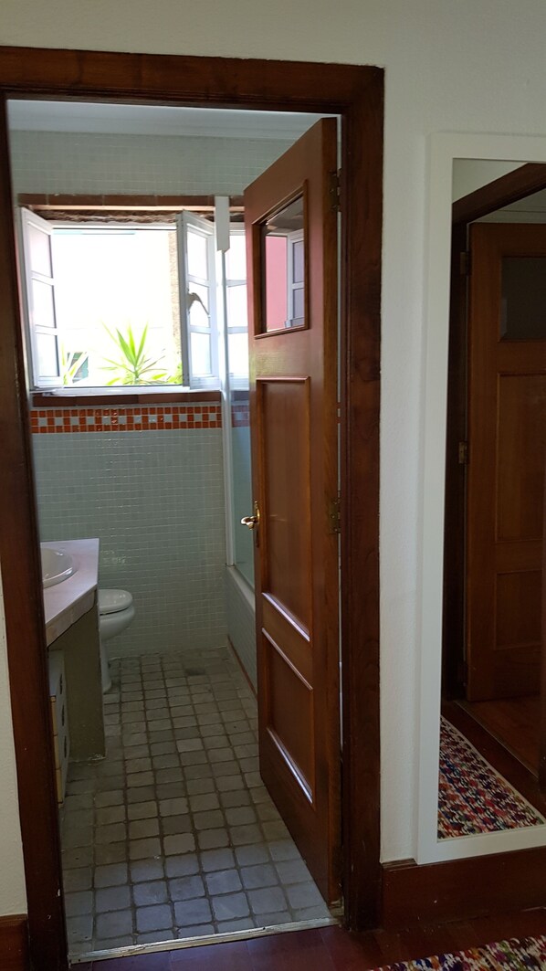 A bathroom with a tiled floor, a toilet, and a sink.