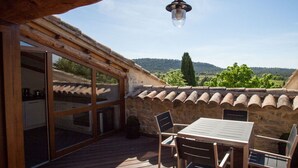 A wooden deck with a table and chairs, overlooking a scenic landscape.