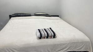 A single bed with a white sheet and a striped pillow. - Embassy Suites. (Winnipeg)