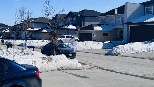 A residential area with houses, a parking lot, and a blue car. - Embassy Suites. (Winnipeg)