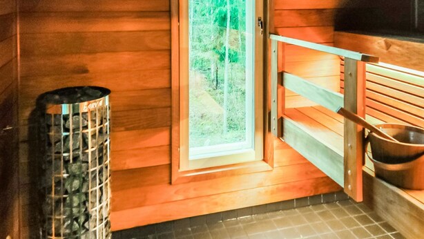 Un sauna con paredes de madera, un banco y un ventanal grande.
