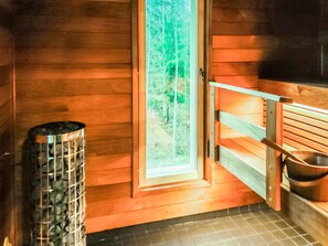 Un sauna avec des murs en bois, un banc et une grande fenêtre.