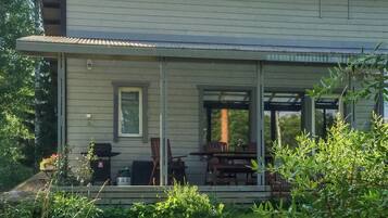 Une maison dotée d’un porche abrité, d’un espace salon extérieur et d’un barbecue.