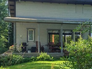 Une maison dotée d’un porche abrité, d’un espace salon extérieur et d’un barbecue.