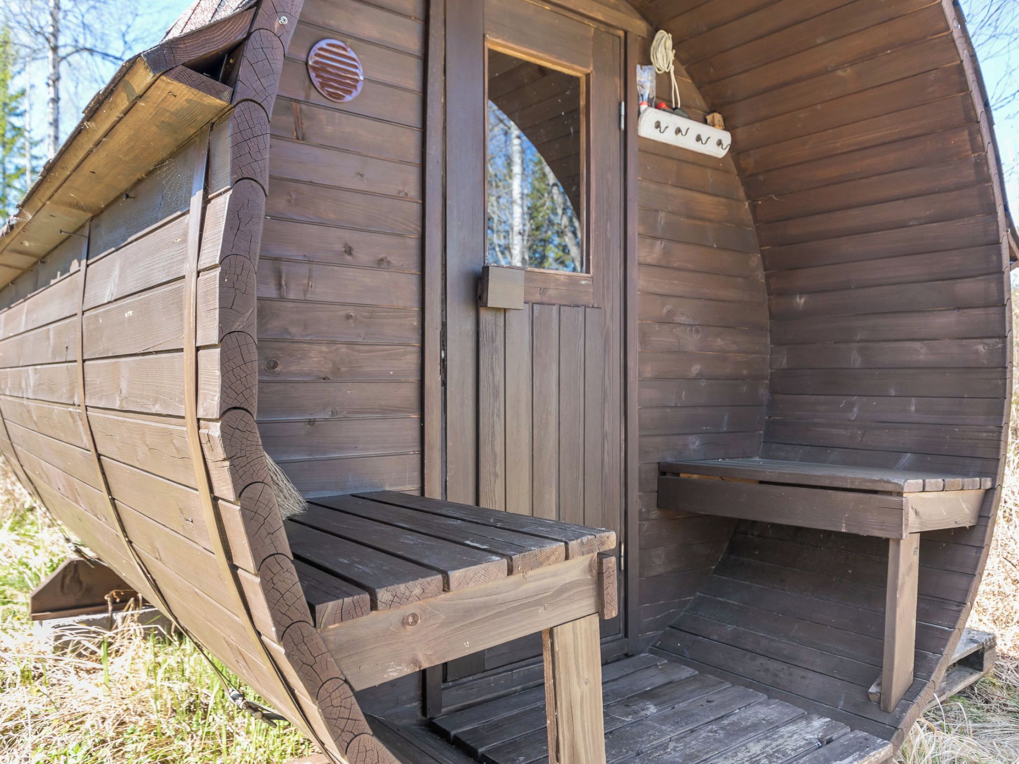 Una cabaña de madera con un banco afuera y una puerta con un letrero.