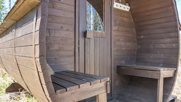 Une cabane en bois avec un banc à l’extérieur et une porte sur laquelle est apposée une pancarte.