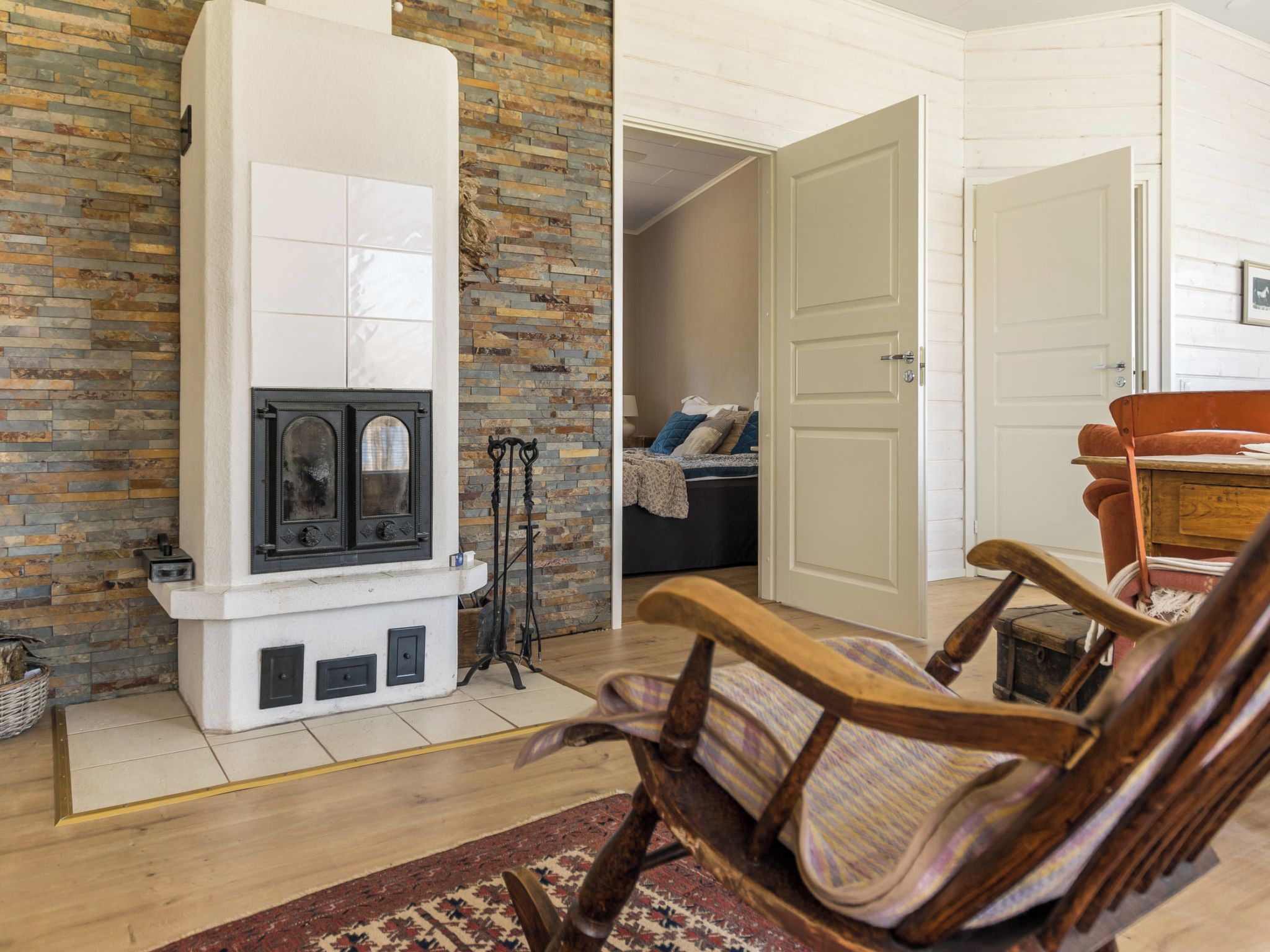 Una sala de estar con chimenea, un sillón de madera y un tapete estampado.