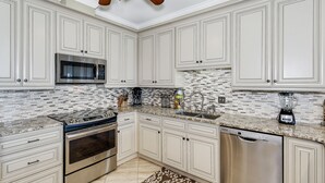 Uma cozinha moderna com armários brancos, eletrodomésticos de aço inoxidável e painel de azulejos.