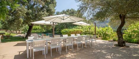 An outdoor patio with a pool, surrounded by trees and greenery.