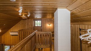 Un interior de madera con una escalera, una pared blanca y un perchero.
