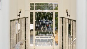 L’entrée d’un hôtel avec une porte en verre, un portail en métal et un sol carrelé.