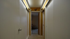 Un couloir étroit doté d’un revêtement de sol en moquette, de boiseries et d’un luminaire au plafond.