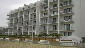 Un immeuble à plusieurs étages doté de balcons, d’une clôture en bois et d’une pelouse devant.