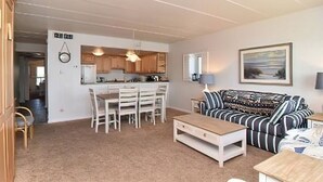 A living room with a sofa, coffee table, and dining area with chairs and a table.