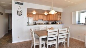 A modern kitchen with wooden cabinets, a central island, and pendant lighting.