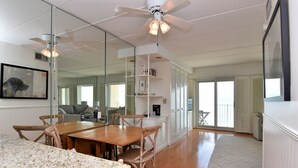 Ein modernes Interieur mit Essbereich, Deckenventilator, großem Spiegel und Blick ins Freie.