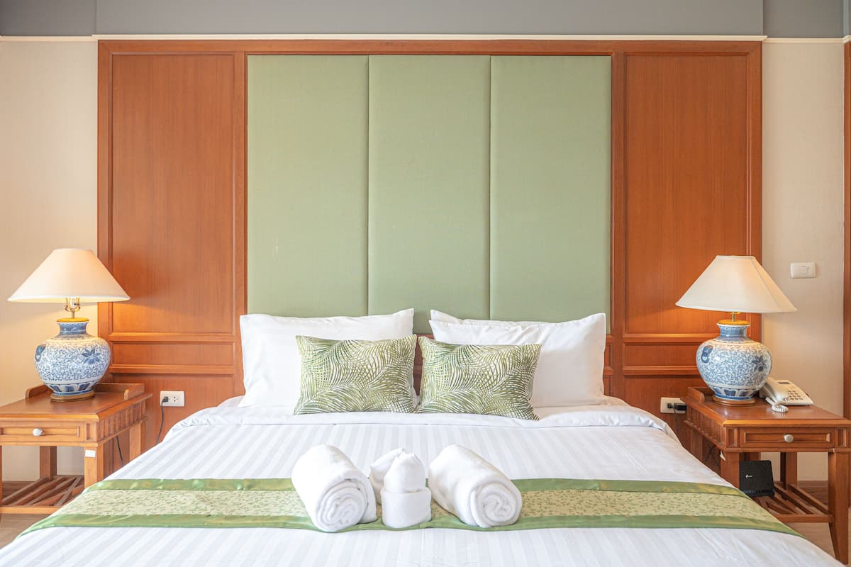 Une chambre d’hôtel avec un grand lit, deux tables de chevet, une tête de lit en bois et deux lampes.