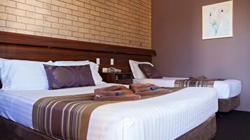 A hotel room with two beds, a brick wall, and a painting.