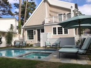 A two-story house with a swimming pool, outdoor seating, and a balcony.