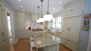Cucina spaziosa con un'isola grande, mobili chiari e illuminazione a sospensione.
