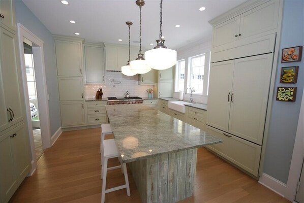 A spacious kitchen with a large island, light-colored cabinets, and pendant lighting.