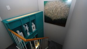 A staircase with teal shelving units and a framed artwork on the wall. - WALK RIGHT ONTO THE BOARDWALK FROM APARTMENT PATIO! (Rehoboth Beach)