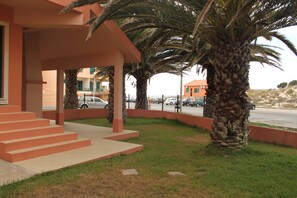 Stroll through the tranquil outdoor space, surrounded by lush palm trees and a covered area with a staircase leading to the entrance.