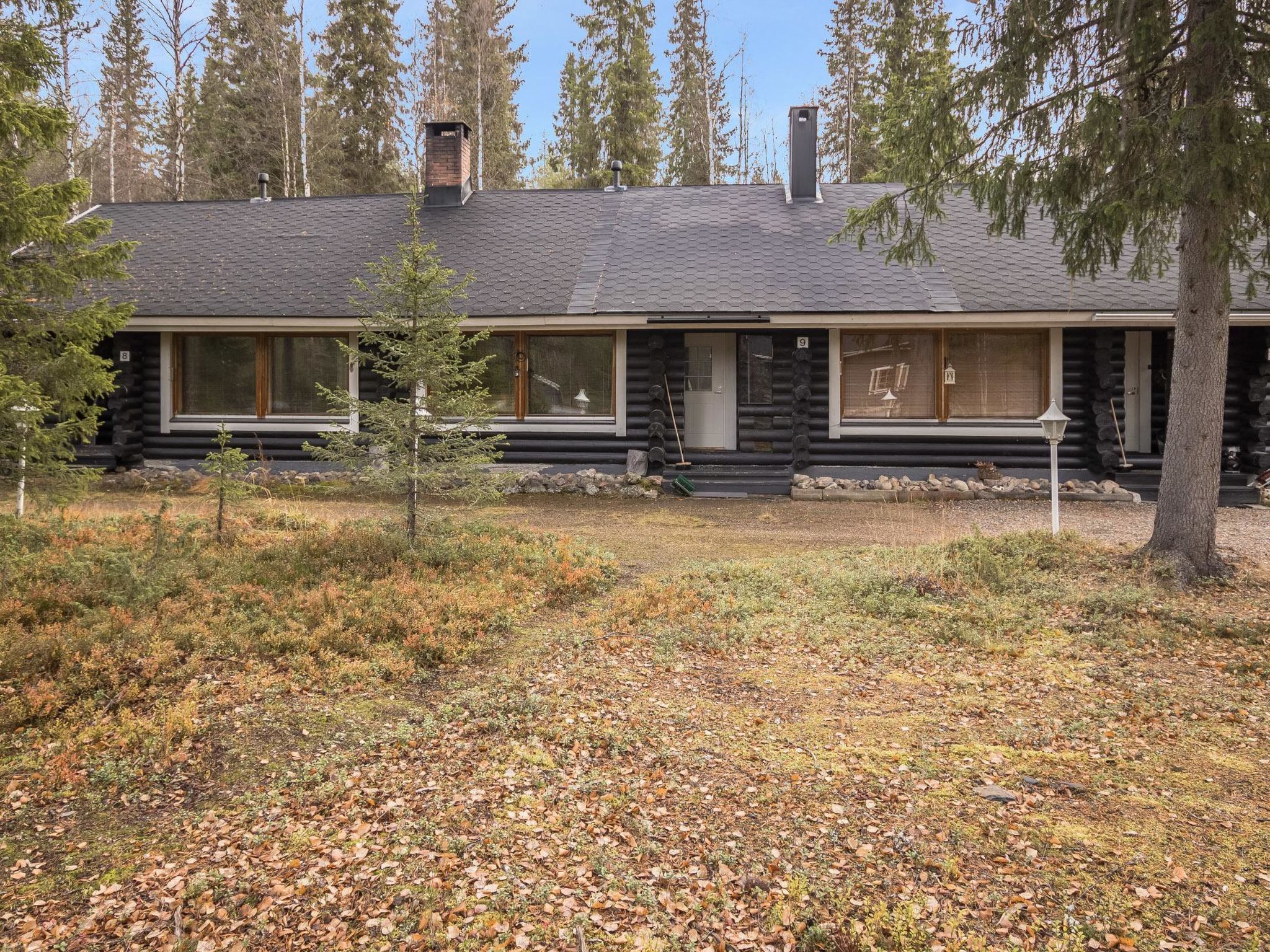 Une cabane en rondins dotée d’une grande véranda à l’avant, de nombreuses fenêtres et d’une cheminée.